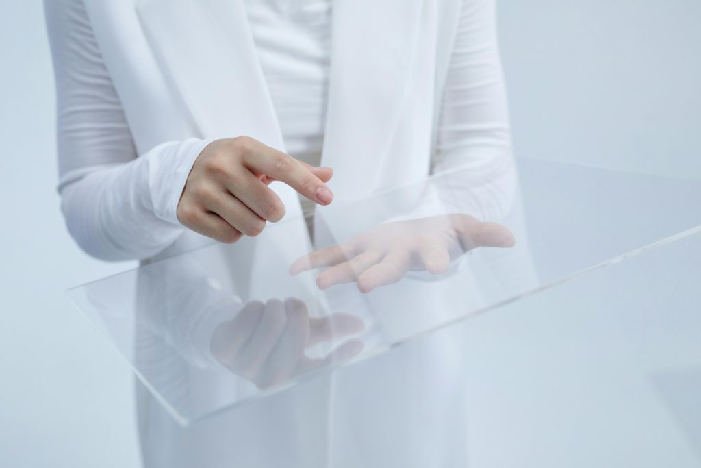Person in white interacting with a clear glass interface, suggesting technological innovation.